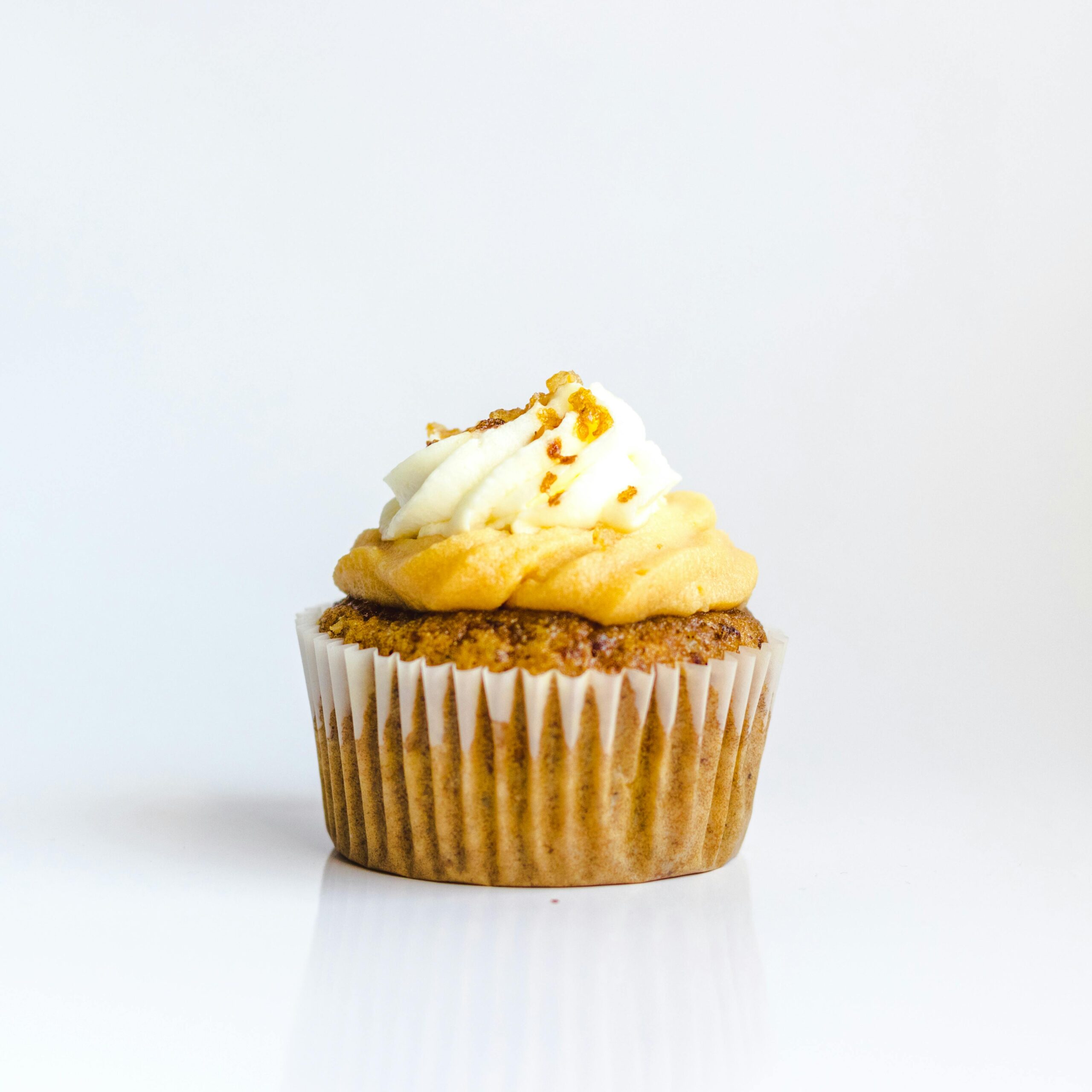 A delectable cupcake with creamy frosting on a white background, perfect for food photography.